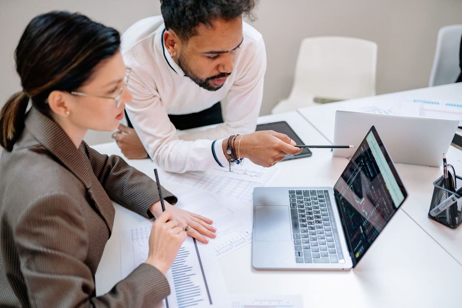 Professionals discussing customer data at a desk with a laptop